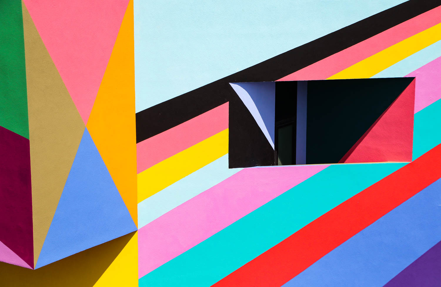 An extreme close up of the brightly coloured geometric mural, in pink, yellow, blue, red, orange and black.